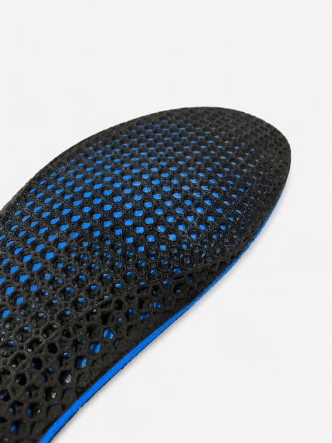 Close-up of a black insole with blue perforated dot pattern and blue edge trim