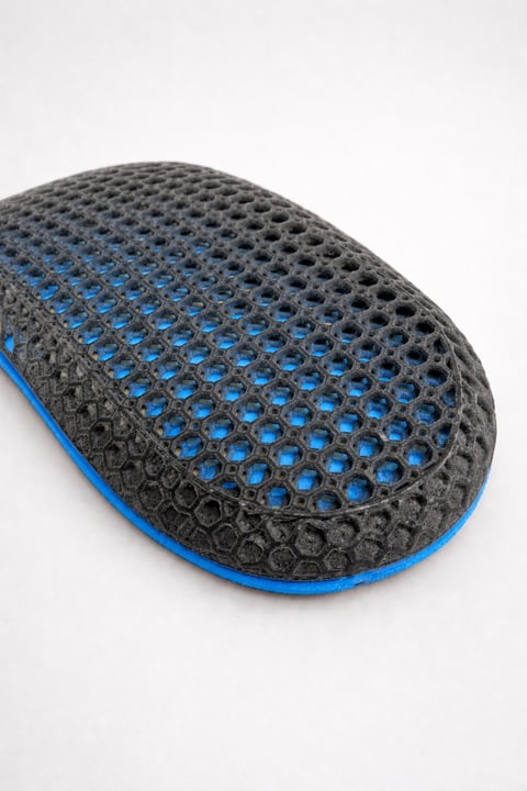 Close-up of a black and blue perforated shoe sole or shoe pad against a white background